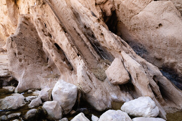 Base of a canyon wall with smooth boulders and textured rock.