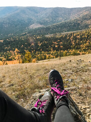 A person is comfortably relaxed on a large rock, with their feet propped up, enjoying and taking in...