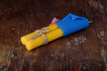 Two blue yellow textured natural bee wax candles tied with jute rope on rustic wooden table...