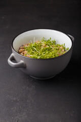Bowl of buckwheat decorated with fresh cress salad microgreen. Watercress shoots on dish as final touch. Vegan, vegetarian trendy food.