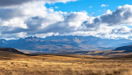 Vast, dry, mountainous landscape under a cloudy sky.  Dry grasslands stretch to the base of distant, rugged peaks