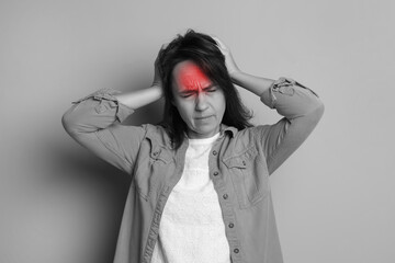 Woman suffering from headache on light background. Black and white effect with red color accent