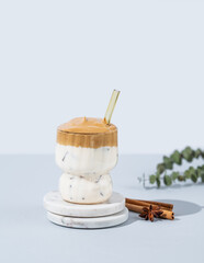 Korean whipped drink Dalgona coffee  on a marble stand on a blue background with cinnamon.