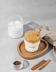 Korean whipped drink Dalgona coffee  on a woden plate on a concrete background with spice and milk jug.