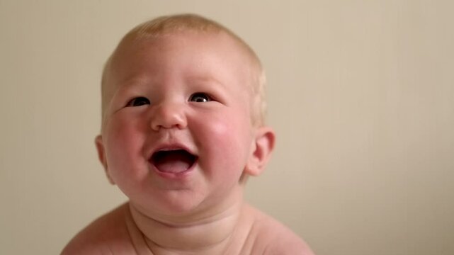 smiling infant baby lies on their tummy, looking up with bright eyes, Cild face expresses pure joy and curiosity, baby emotions, childhood happiness, home comfort