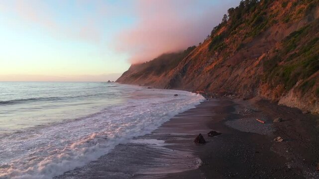 Northern California waves crashing bluffs cliffside mountain rocky rugged remote coast aerial drone vibrant sunset USAL Beach Campground Sinkyone Wilderness surf swell black sand forward slowly motion