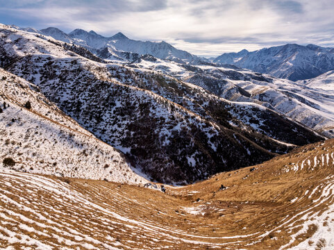 Trails on a Sun-scorched Hillside. A wintry evening landscape with a trails on a hillside, snow-capped mountains in the background