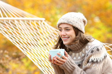 Happy woman drinking and thinking in nature in autumn