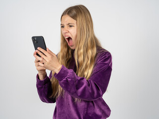 Angry beautiful teen girl wearing purple sweater screaming on the phone, having an argument with an employee. Troubles at work.