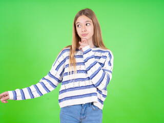 Thoughtful beautiful teen girl wearing striped sweater holds chin and looks away pensively makes up great plan