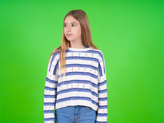 beautiful teen girl wearing striped sweater stares aside with wondered expression has speechless expression. Embarrassed model looks in surprise