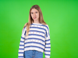 Portrait of dissatisfied beautiful teen girl wearing striped sweater smirks face, purses lips and...