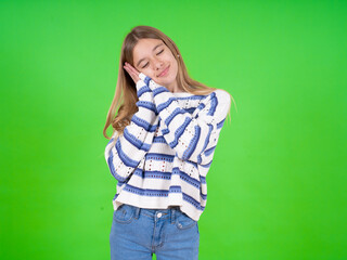 beautiful teen girl wearing striped sweater leans on pressed palms closes eyes and has pleasant...