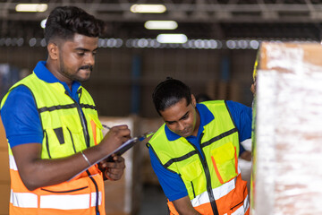 Two warehouse workers checking inventory and organizing packages during a busy day at a distribution center