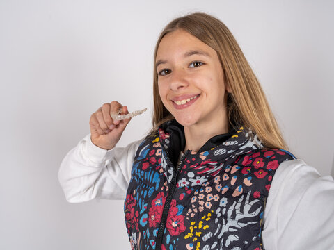 beautiful teen girl wearing colorful vest  make selfie holding an invisible braces aligner, recommending this new treatment. Dental healthcare concept.