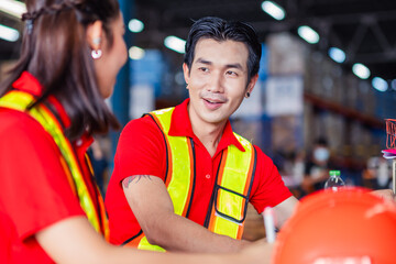 Employees discussing logistics while working in a warehouse during daytime hours in a vibrant environment