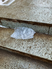A plastic shopping bag is resting on a staircase made of concrete, marble, or granite, drawing attention to the distinctive architectural features of the building surrounding it