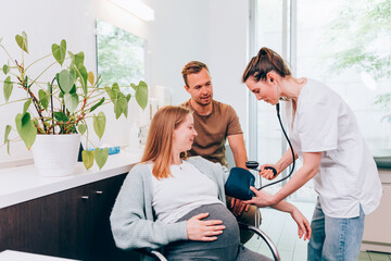 Pregnant woman having blood pressure checked by doctor