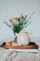 Warm setting with floral arrangement and teapot on wooden tray,