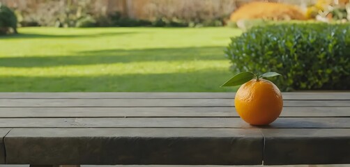 Photo of a fresh orange without leaves on a wooden table with an orange grove in the background