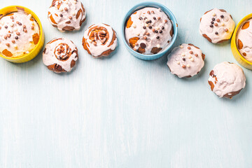 Cupcakes and muffins or Easter cakes poured with white icing on a light blue table. Space for text....