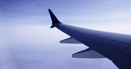 Fototapeta premium Wing of an airplane cruising above the clouds 