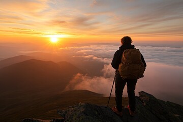 Hiker enjoying a breathtaking sunset view from a mountain peak above the clouds during golden hour