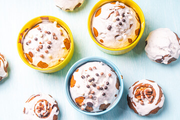 Cupcakes and muffins or Easter cakes poured with white icing on a light blue table. Space for text. View from above. Flat layout