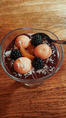 Delicious chocolate pudding with biscuits, blackberries and candied orange zest on wooden table strbske pleso, high tatras