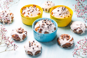 Cupcakes and muffins or Easter cakes poured with white icing on a light blue table. Space for text....