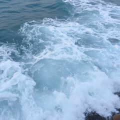 Fototapeta premium Cresting ocean waves, tranquil blue water with frothy white caps, perfect backdrop for beach-themed designs or relaxation content.