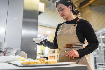 Pastry chef sprinkling icing sugar on freshly baked pastries