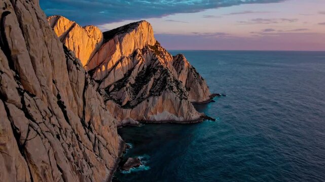 Warm sunlight paints the steep cliffs of Capo Caccia, Sardinia, creating a breathtaking coastal panorama at sunset