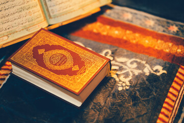 A beautifully quran book resting on a patterned cloth, surrounded by other texts, symbolizing...