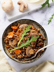 Top view of buckwheat porridge dish with mushrooms, carrots and lettuce, healthy eating concept
