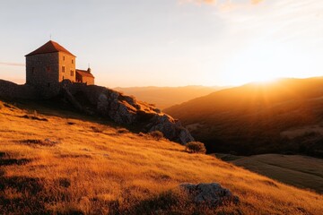 Sunset over a historic stone building on a hilltop in a serene landscape