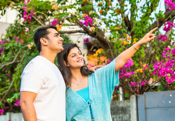 Young Indian couple sharing a joyful morning nature walk, smiling, pointing, and bonding together