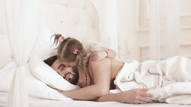 Little daughter wakes up her father by kissing him