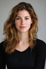 Fototapeta premium A woman with long brown hair and a black shirt is smiling