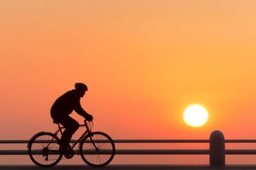 Obraz premium Cyclist rides along waterfront at sunset with vibrant colors in the sky