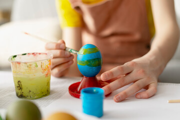 Child painting easter eggs with brush and tempera colors