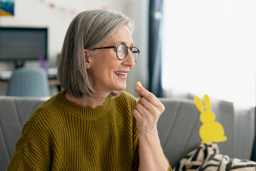 Happy Senior Woman Eating Easter Egg at Home