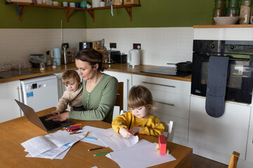 Mother working from home and multitasking caring for her young children