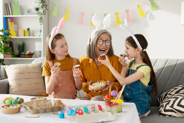 Grandchildren sharing chocolate easter eggs with grandmother