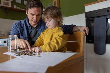 Father Helping Child Count Coins at Kitchen Table