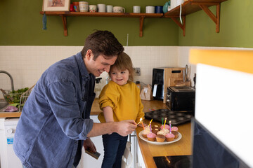 Father lighting candles on cupcakes for a birthday celebration