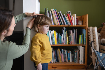 Mother Measuring a child's height against the wall