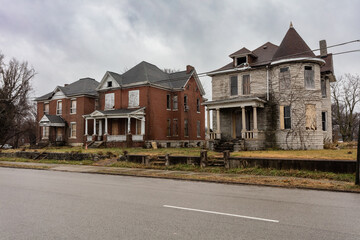 3 vintage abandoned houses on empty street with overcast sky in East St. Louis