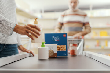 Customer placing groceries on the checkout conveyor belt