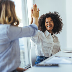 Two Happy Businesswomen Celebrating Success With High Five in Office
